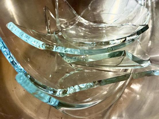A metal bowl filled with the remnants of a glass bowl. The glass bowl shards have that attractive celadon colour.