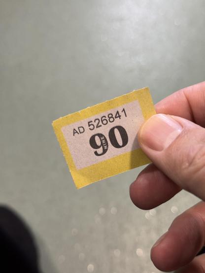 Me holding a numbered ticket, saying 90.