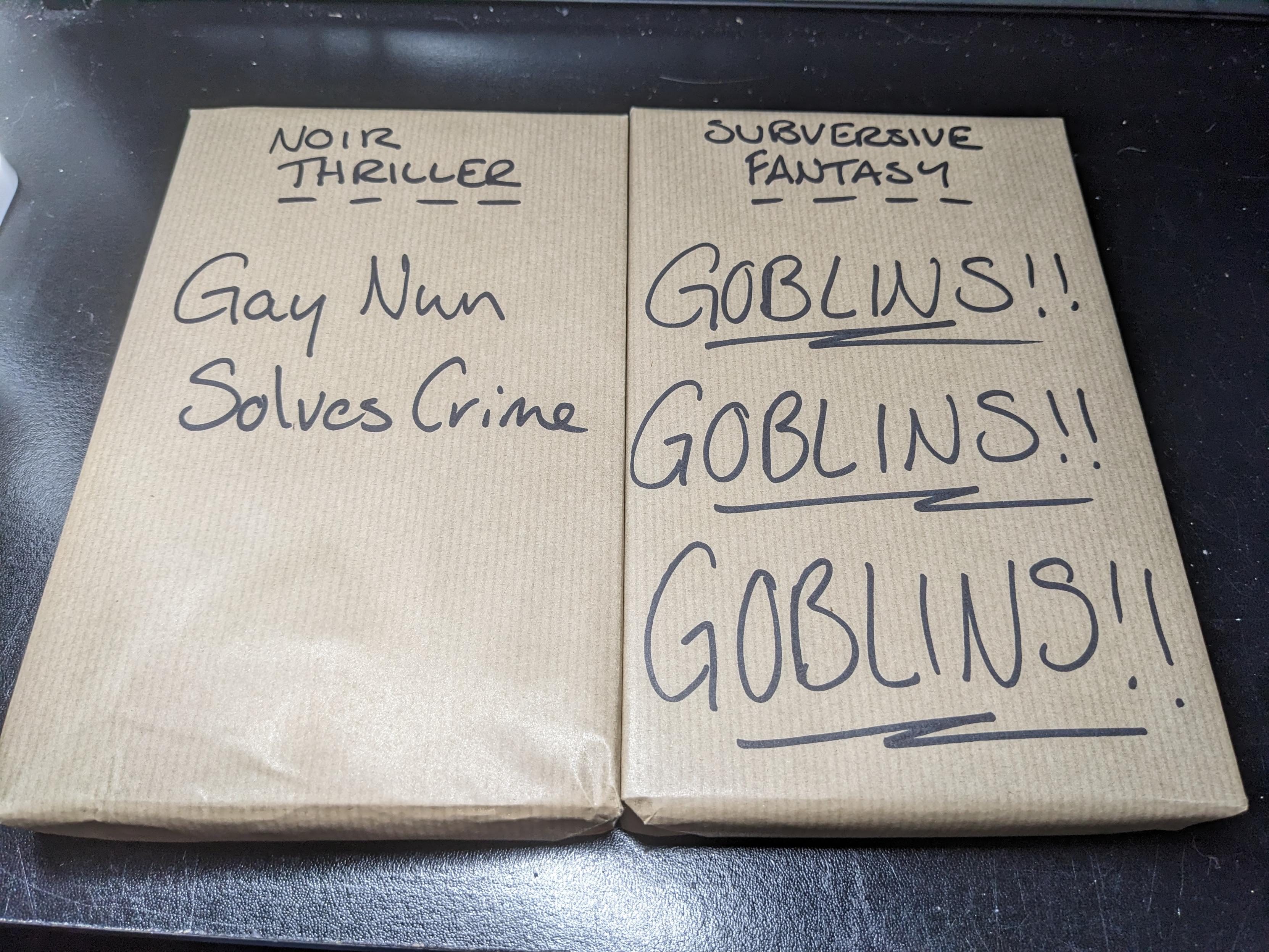 Two books wrapped in brown paper so you can't see the covers; each has a short description written on it in black marker pen. The book on the left says "Noir thriller. Gay nun solves crime" and the book on the right says "Subversive fantasy. Goblins!! Goblins!! Goblins!!"