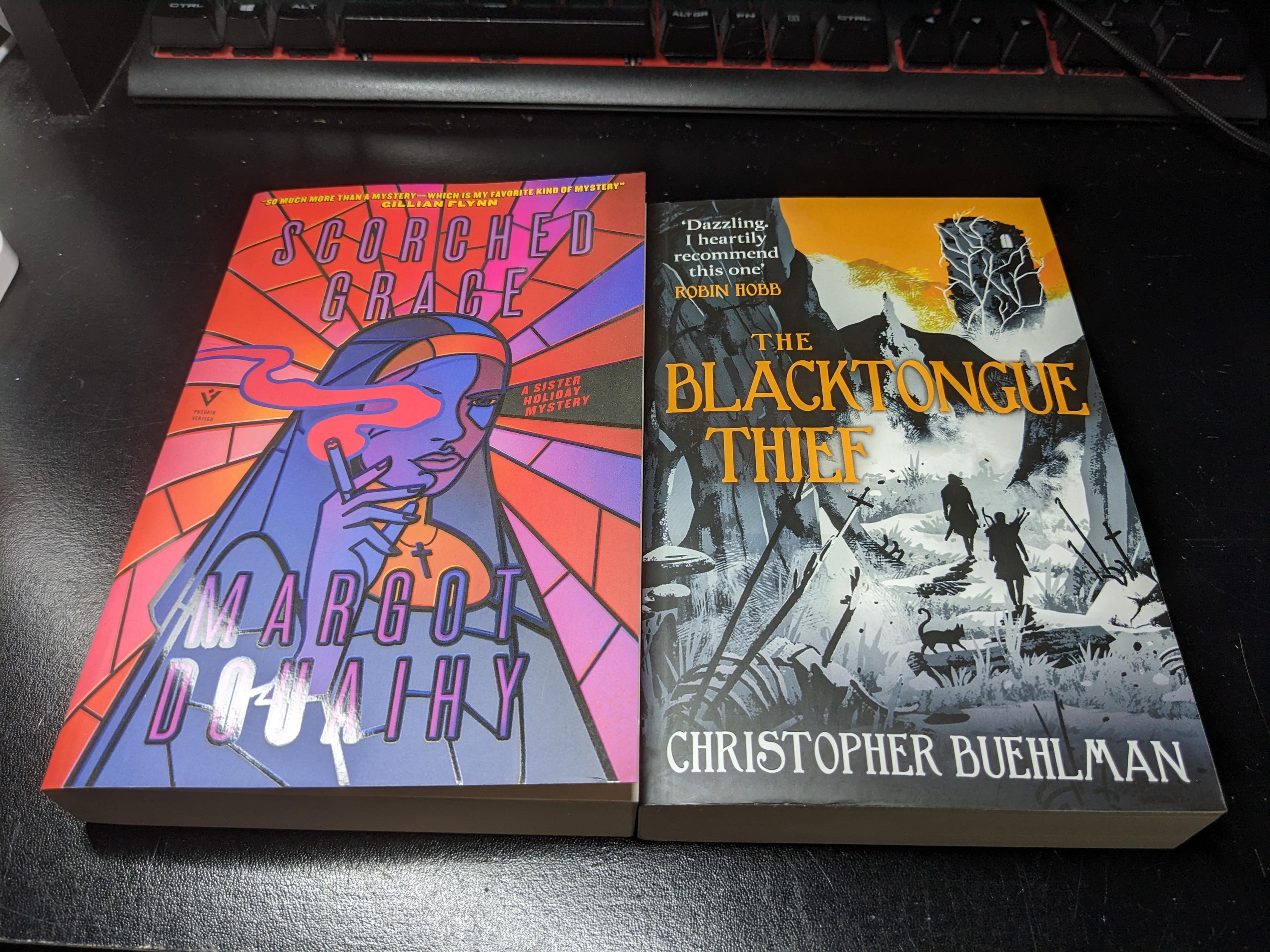 Two paperback books, now without secretive brown paper wrapping. "Gay nun solves crime" turned out to be Scorched Grace by Margot Douaihy. "Goblins!! Goblins!! Goblins!!" is The Blacktongue Thief by Christopher Buehlman.