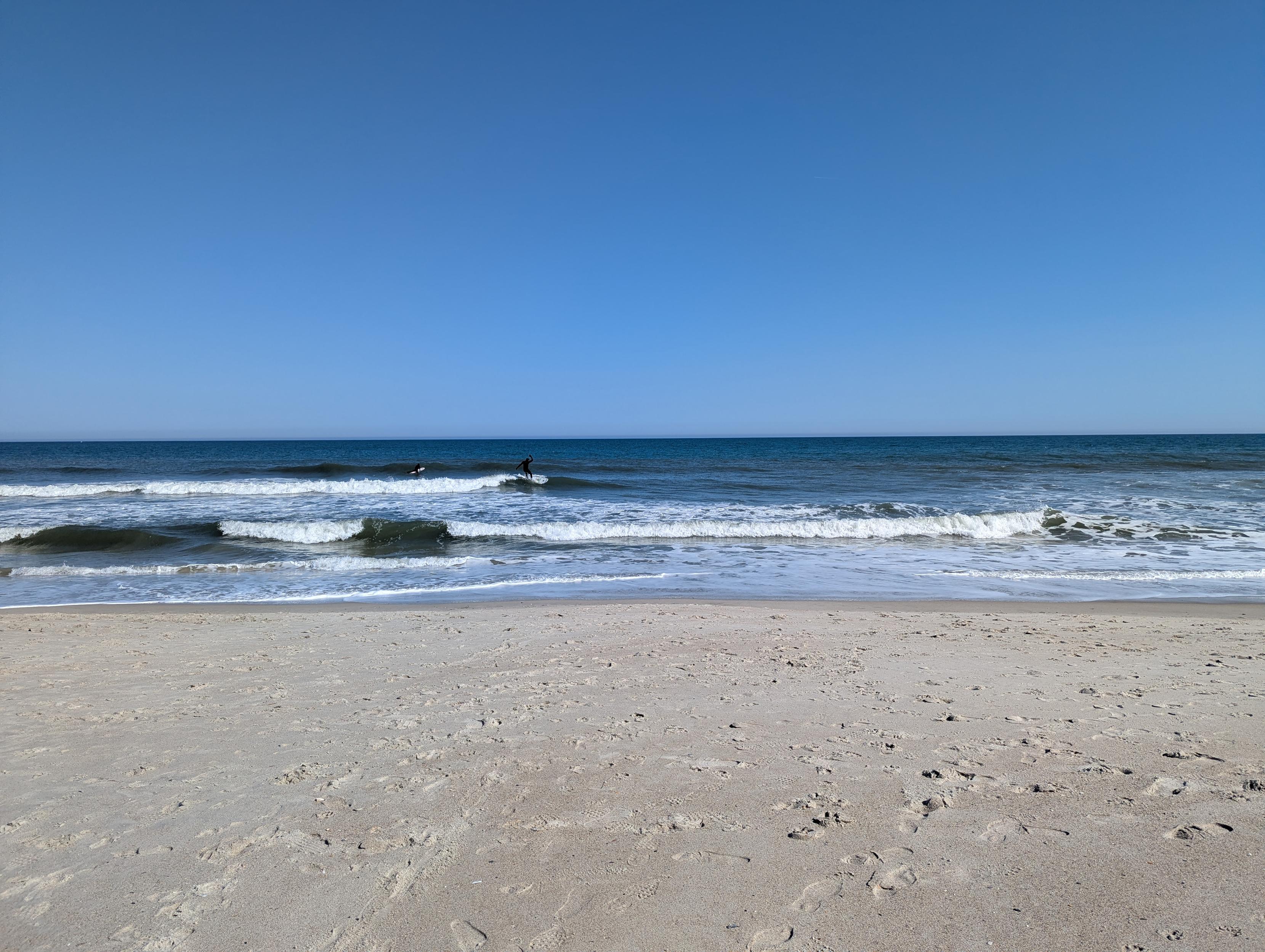 Snapshot of an ocean beach. Small waves, but there's a surfer doing the best with what is available