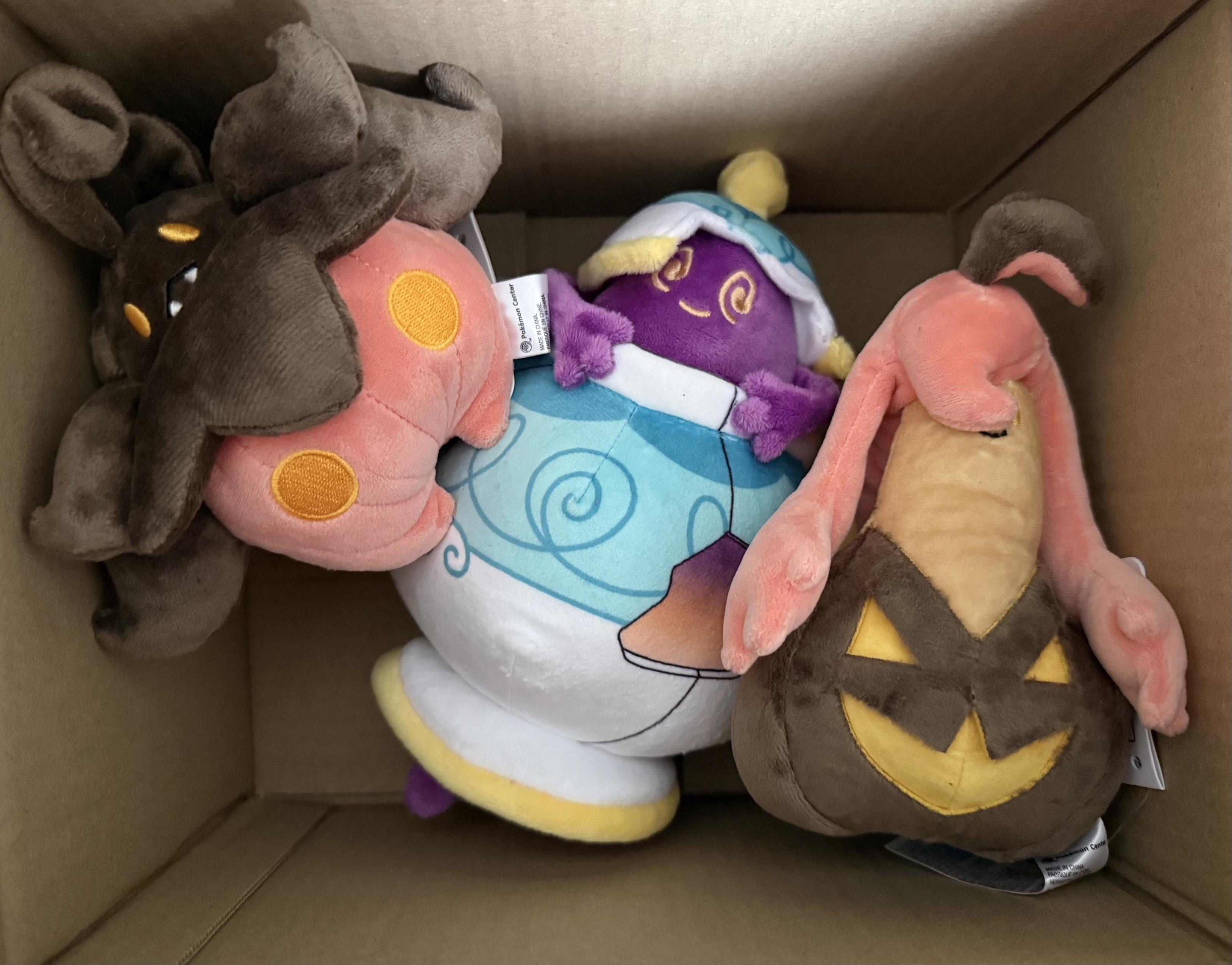 A pumpkaboo, poulteageist and gourgeist plush in a cardboard box.
